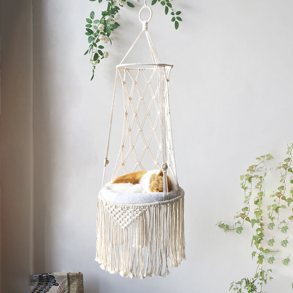 Macrame hanging chair with fringes against a light gray wall with plants.