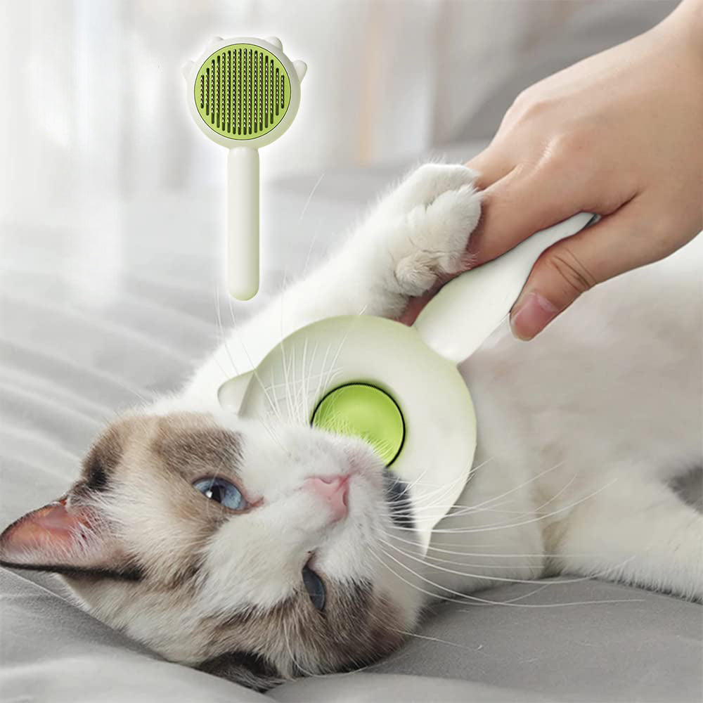 Cat being groomed with a green pet grooming brush held by a hand.