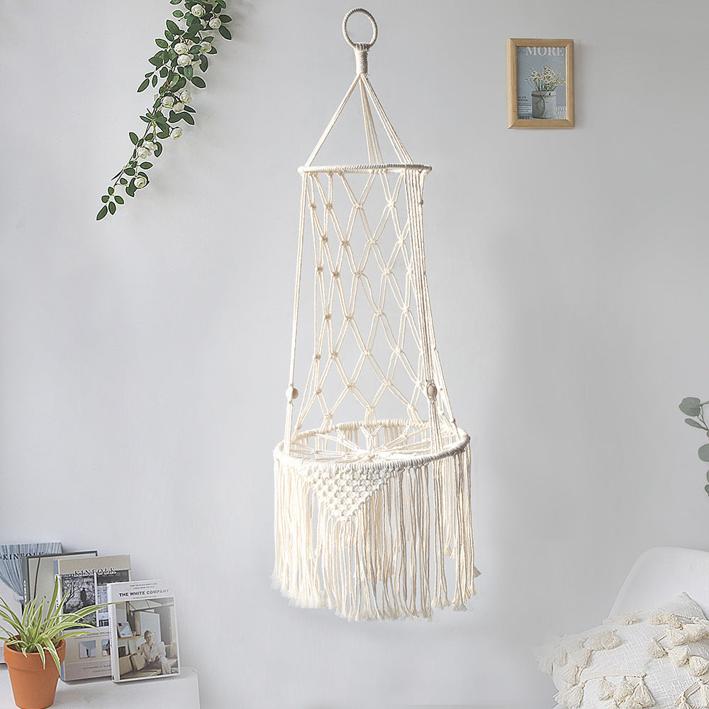 Macrame hanging chair with lights on a white wall with decorative elements.